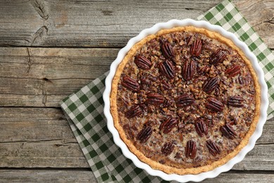 Delicious pecan pie in baking dish on wooden table, top view. Space for text