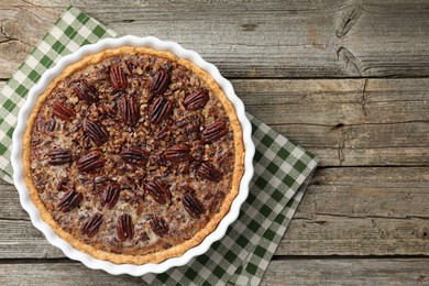 Photo of Delicious pecan pie in baking dish on wooden table, top view. Space for text