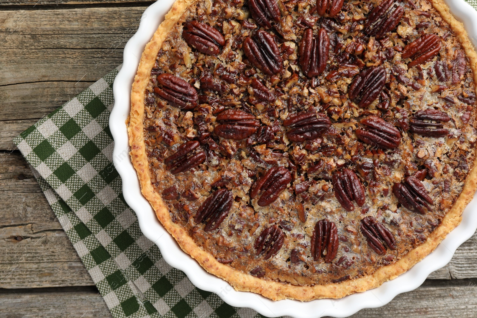 Photo of Delicious pecan pie in baking dish on wooden table, top view.