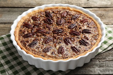 Delicious pecan pie in baking dish on wooden table, closeup