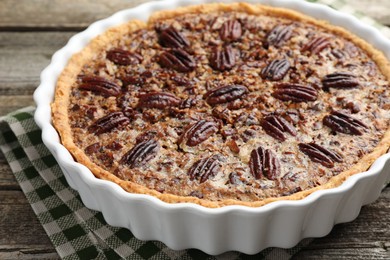 Photo of Delicious pecan pie in baking dish on wooden table, closeup