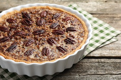 Photo of Delicious pecan pie in baking dish on wooden table, closeup