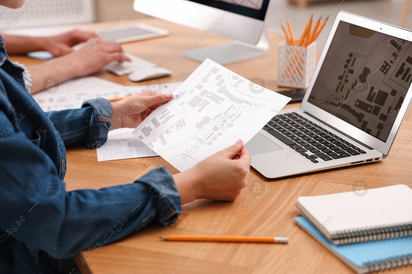 Photo of Cartographer working with cadastral map at wooden table, closeup