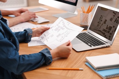 Photo of Cartographer working with cadastral map at wooden table, closeup