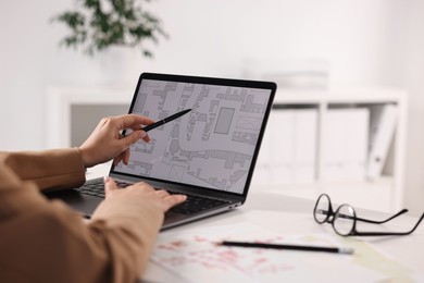 Photo of Cartographer working with cadastral map on laptop at white table in office, closeup