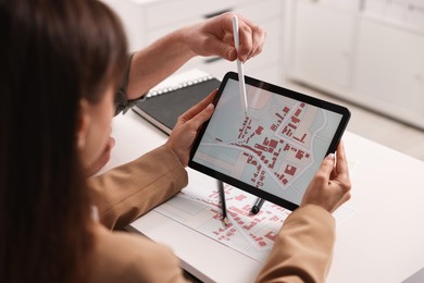 Photo of Cartographers working with cadastral map on tablet at white table in office, closeup