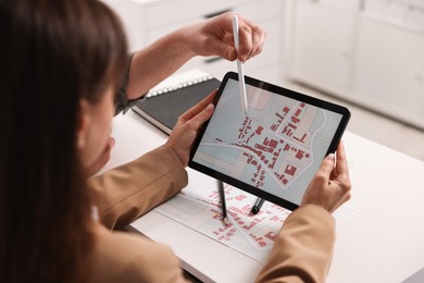 Cartographers working with cadastral map on tablet at white table in office, closeup