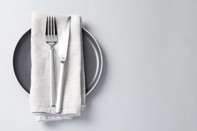 Photo of Stylish silver cutlery, plate and napkin on white background, top view. Space for text