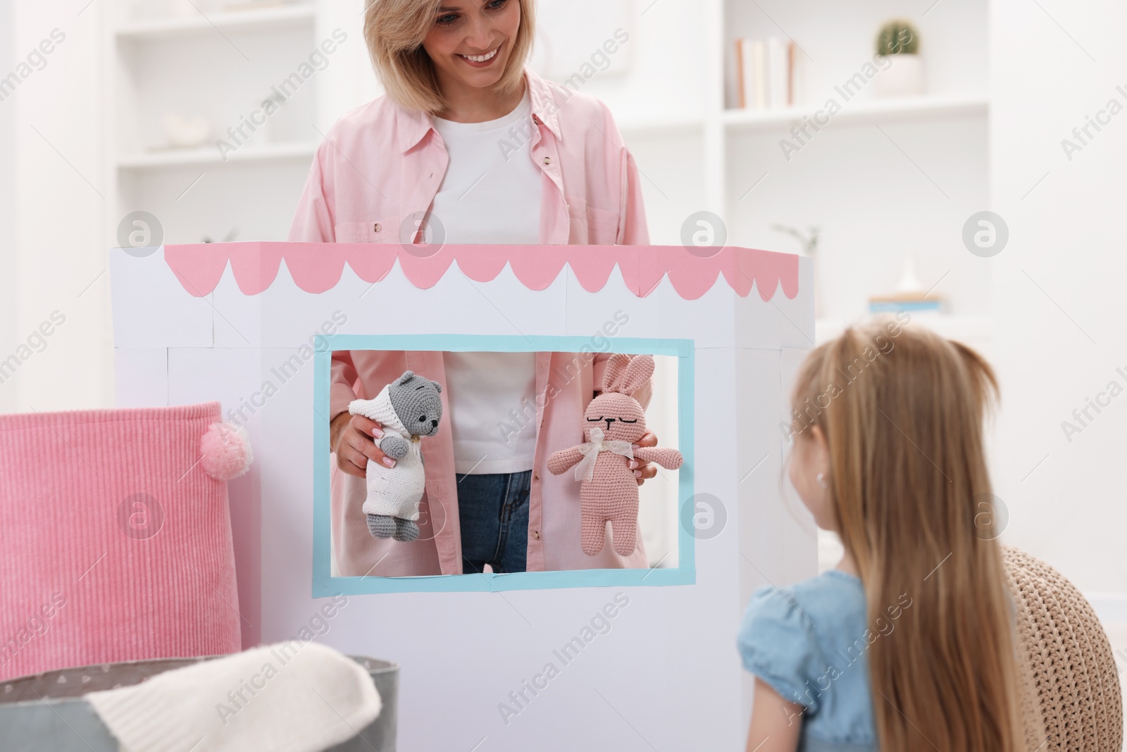 Photo of Puppet theatre. Smiling mother performing show with toys to her daughter at home