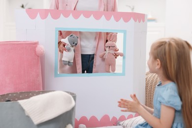 Photo of Puppet theatre. Mother performing show with toys to her daughter at home, closeup