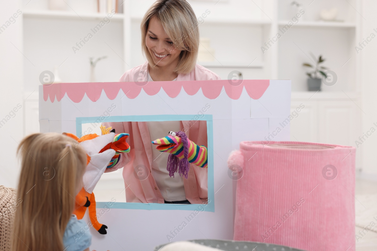 Photo of Puppet theatre. Smiling mother performing show to her daughter at home