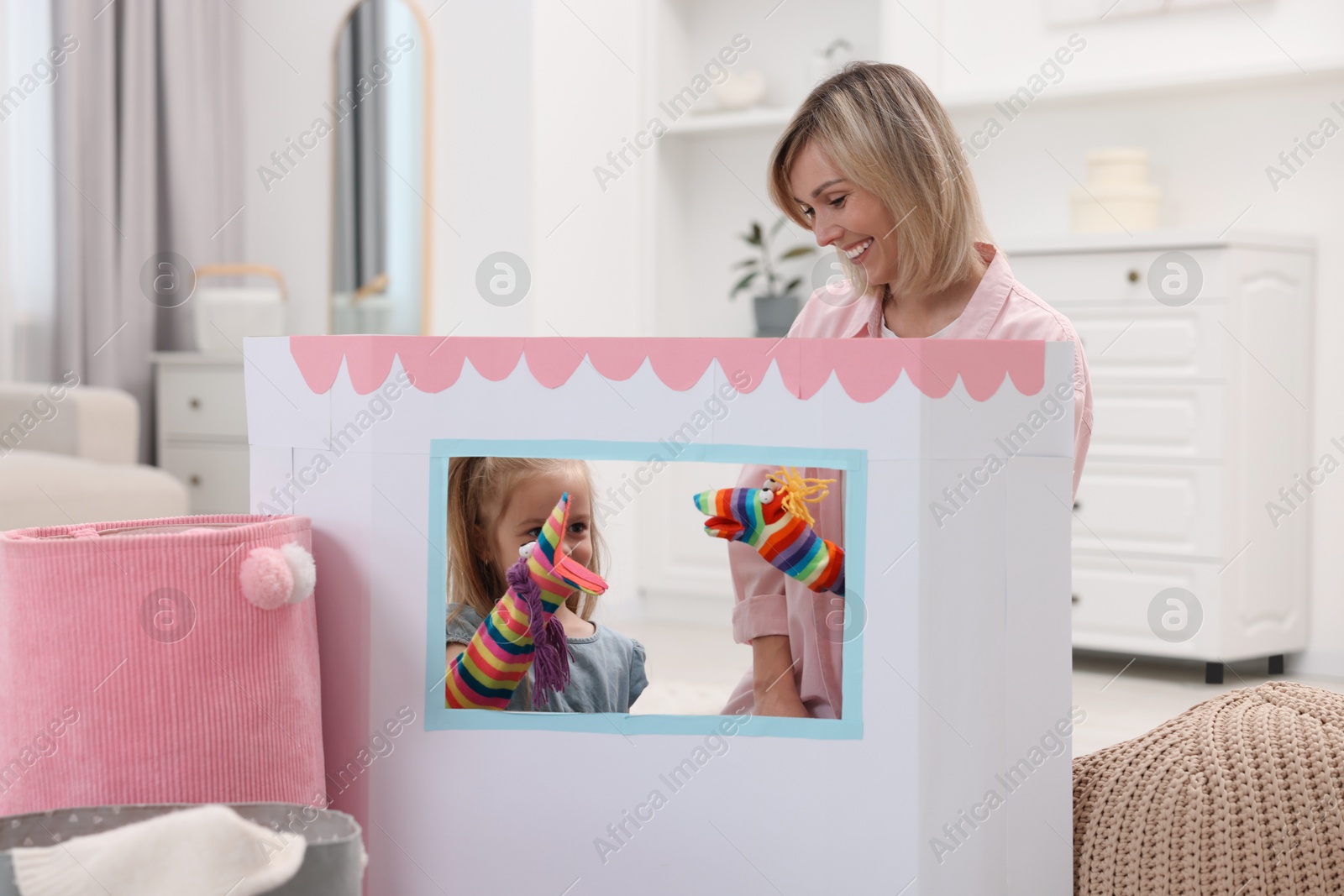 Photo of Puppet theatre. Girl playing toys with her smiling mother at home