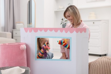 Photo of Puppet theatre. Girl playing toys with her smiling mother at home