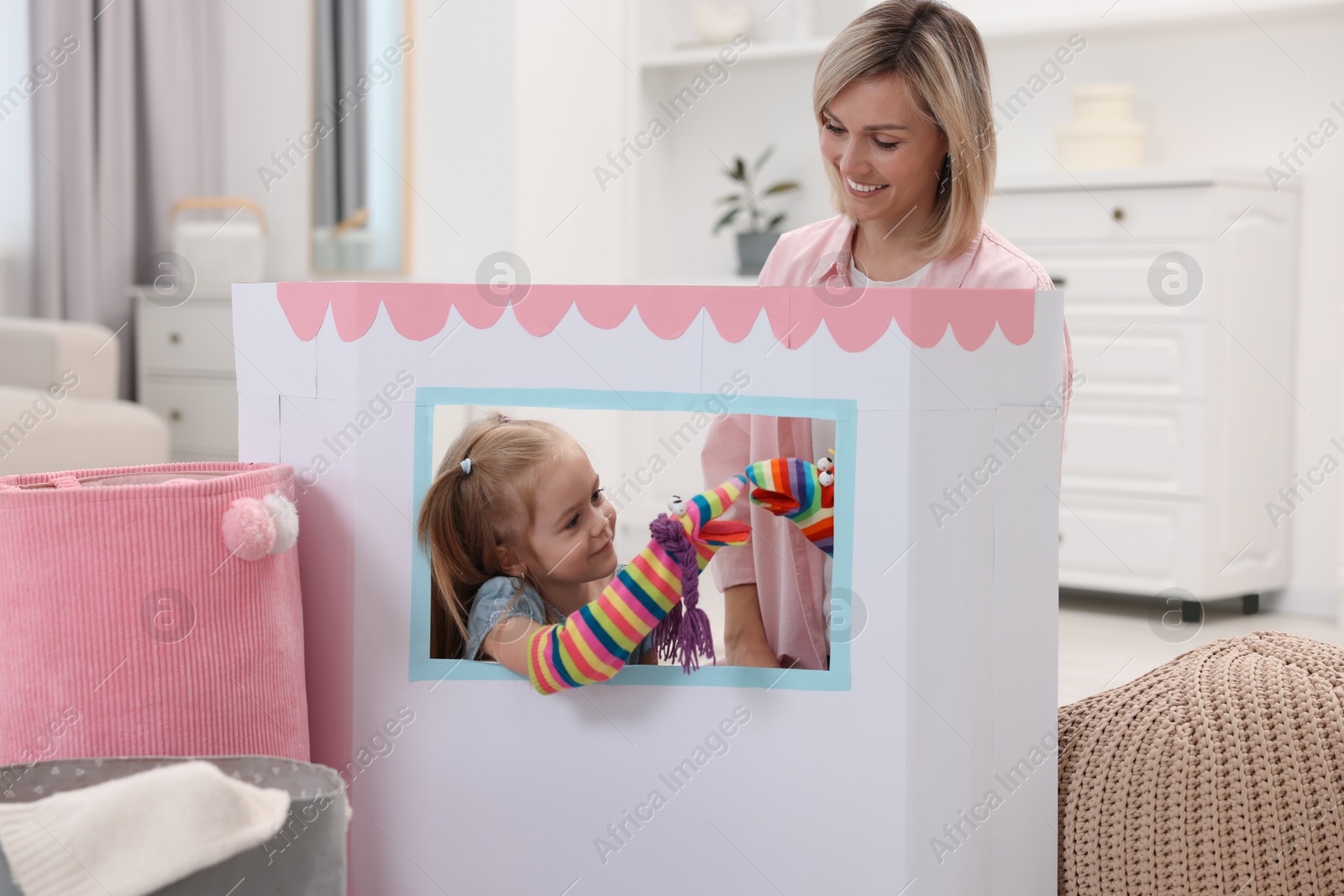 Photo of Puppet theatre. Girl playing toys with her smiling mother at home