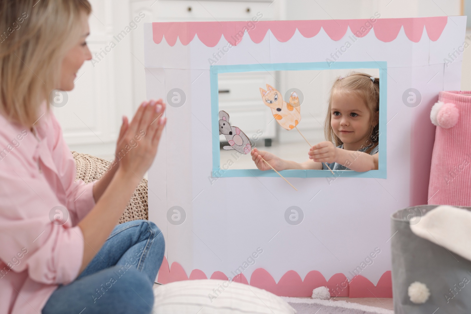 Photo of Puppet theatre. Girl performing show with toy to her mother at home