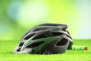 Stylish protective helmet on green grass against blurred background