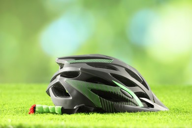 Photo of Stylish protective helmet on green grass against blurred background
