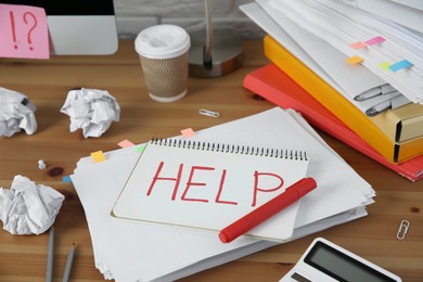 Photo of Notebook with word Help and stationery on wooden table at workplace