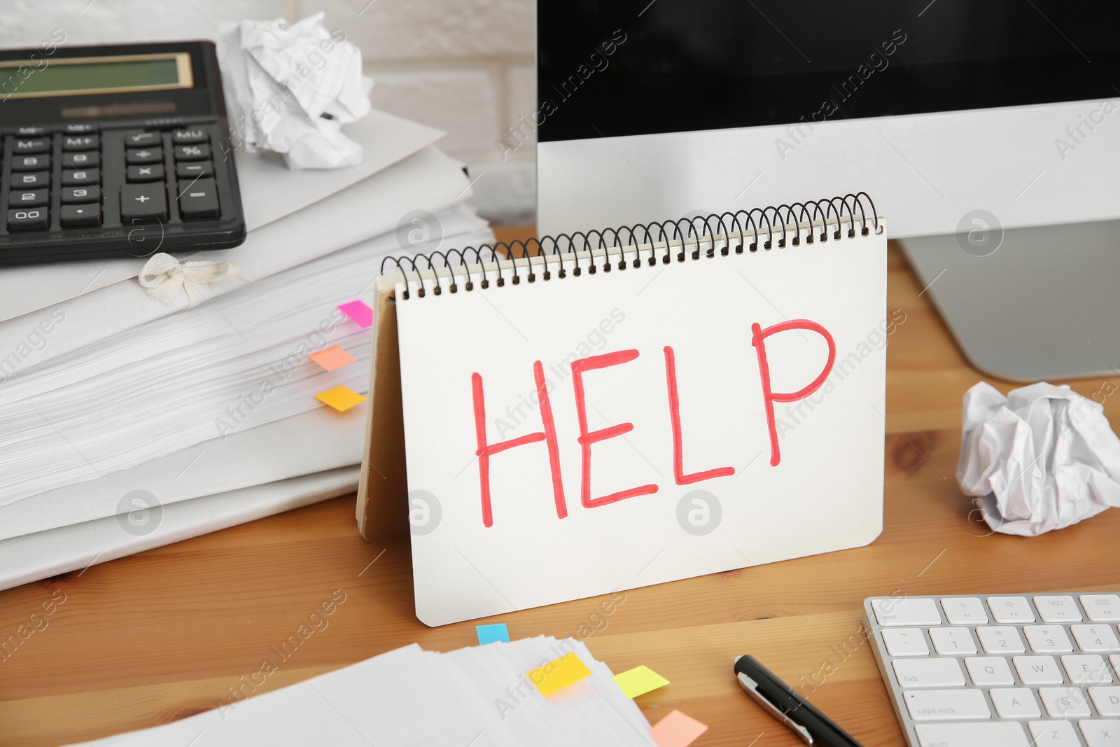 Photo of Notebook with word Help, computer and stationery on wooden table at workplace