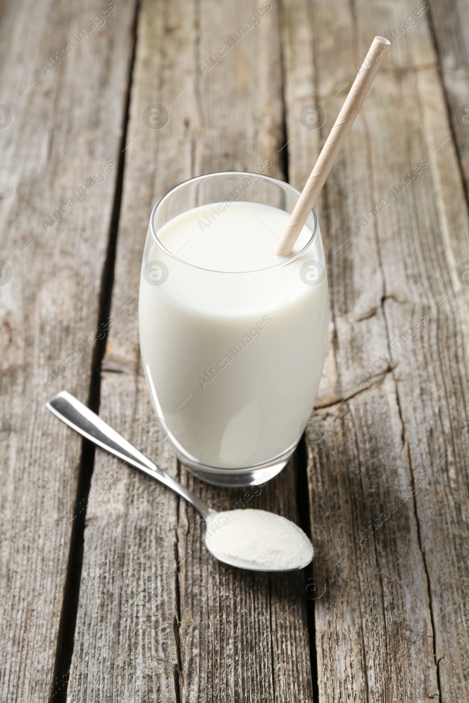 Photo of Delicious protein shake in glass and spoon with powder on wooden table