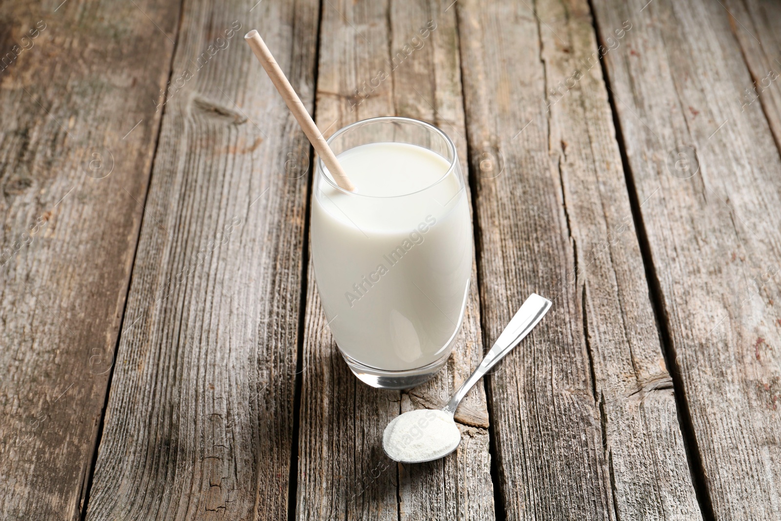 Photo of Delicious protein shake in glass and spoon with powder on wooden table