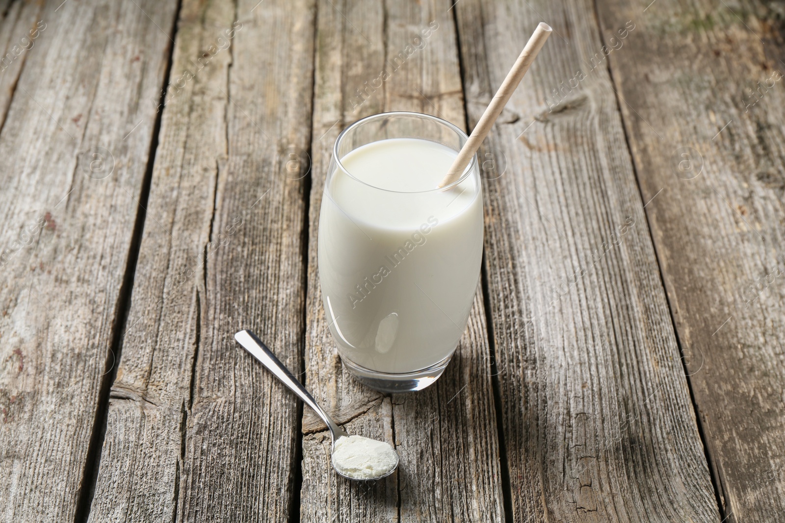 Photo of Delicious protein shake in glass and spoon with powder on wooden table