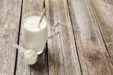 Photo of Delicious protein shake in glass and scoop with powder on wooden table, space for text