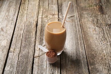 Delicious protein shake in glass and scoop with powder on wooden table