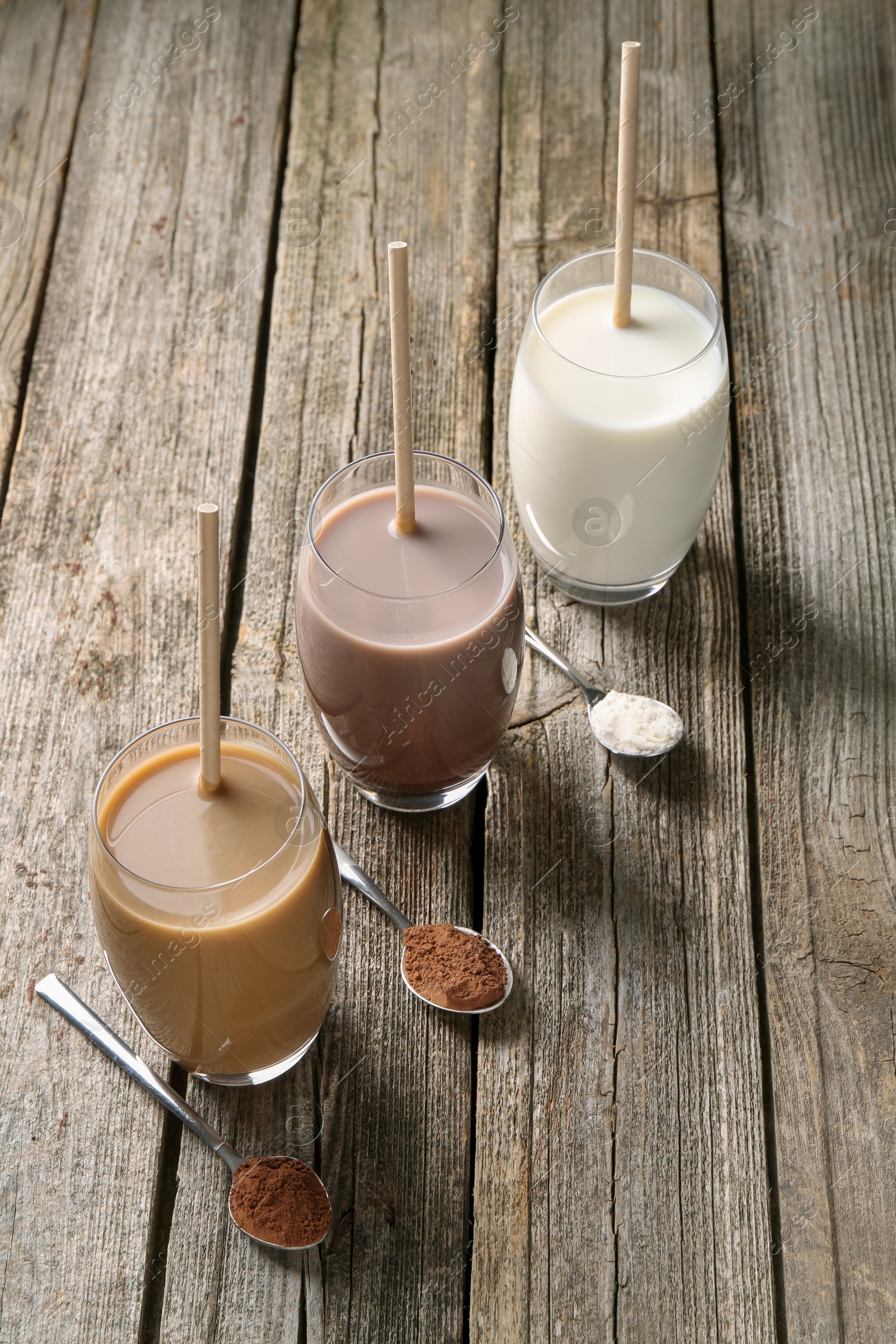 Photo of Delicious protein shakes in glasses and spoons with powder on wooden table