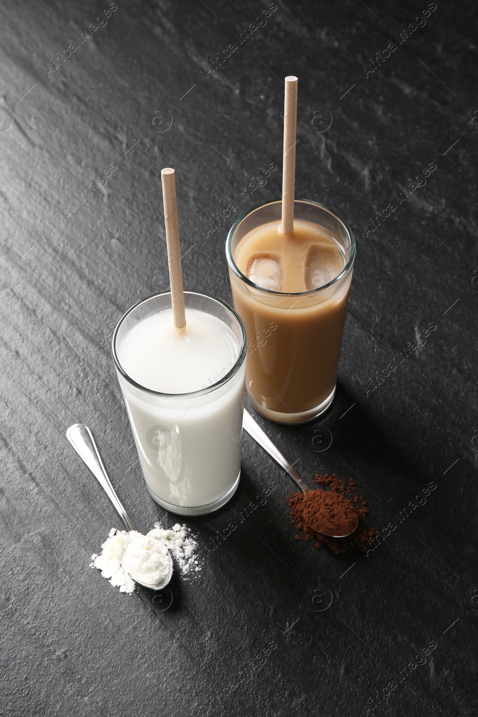 Photo of Delicious protein shakes in glasses and spoons with powder on black table