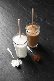 Photo of Delicious protein shakes in glasses and spoons with powder on black table