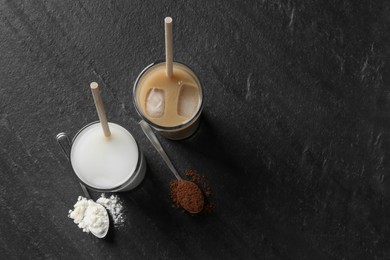 Photo of Delicious protein shakes in glasses and spoons with powder on black table, flat lay. Space for text