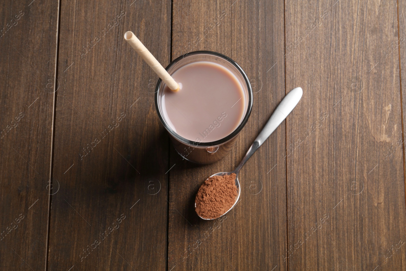 Photo of Delicious protein shake in glass and spoon with powder on wooden table, top view