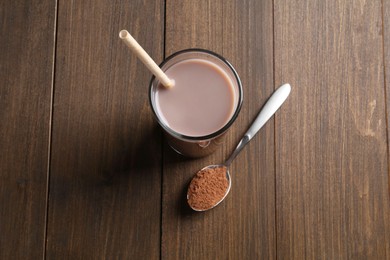 Photo of Delicious protein shake in glass and spoon with powder on wooden table, top view