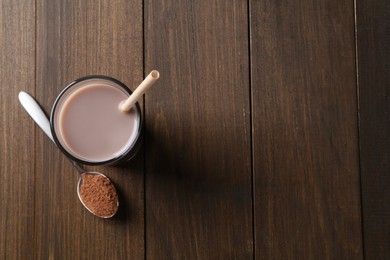 Photo of Delicious protein shake in glass and spoon with powder on wooden table, top view. Space for text