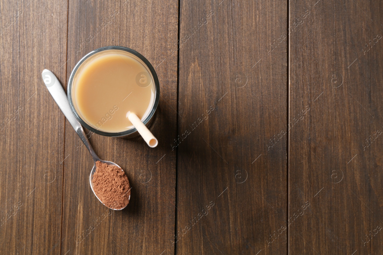 Photo of Delicious protein shake in glass and spoon with powder on wooden table, top view. Space for text