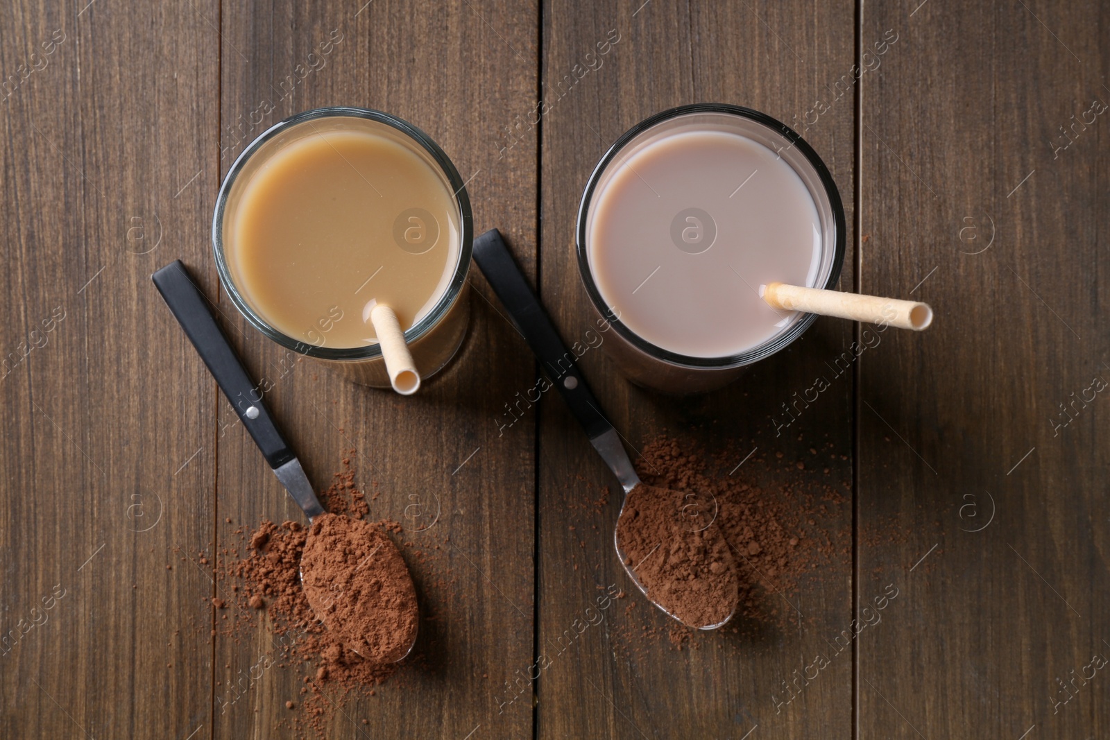 Photo of Delicious protein shakes in glasses and spoons with powder on wooden table, top view