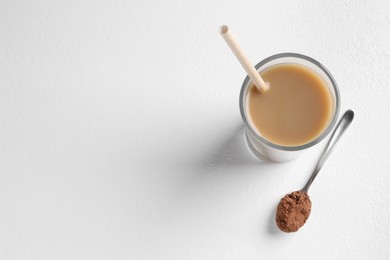 Photo of Delicious protein shake in glass and spoon with powder on white background, top view. Space for text