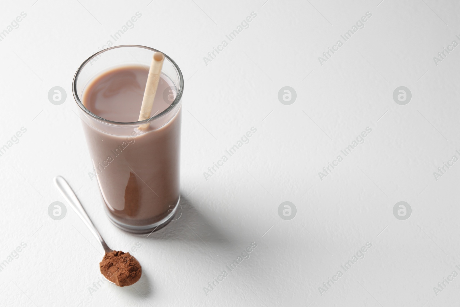 Photo of Delicious protein shake in glass and spoon with powder on white background, space for text