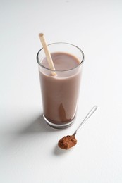 Delicious protein shake in glass and spoon with powder on white background