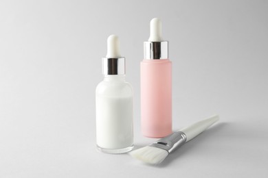 Photo of Bottles of chemical peel and brush on light background. Peeling procedure