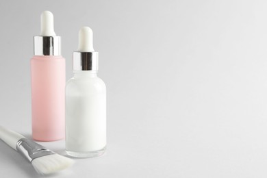 Photo of Bottles of chemical peel and brush on light background, space for text. Peeling procedure