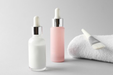 Bottles of chemical peel, towel and brush on light background. Peeling procedure