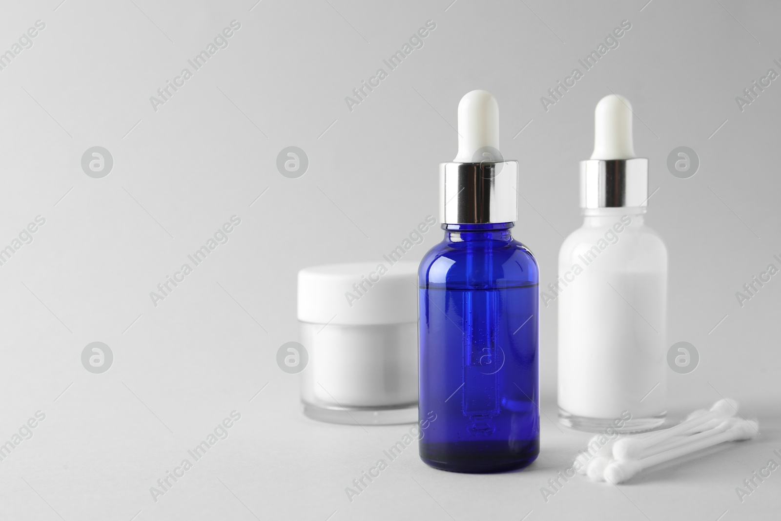 Photo of Bottles of chemical peel, jar and cotton swabs on light background, space for text. Peeling procedure