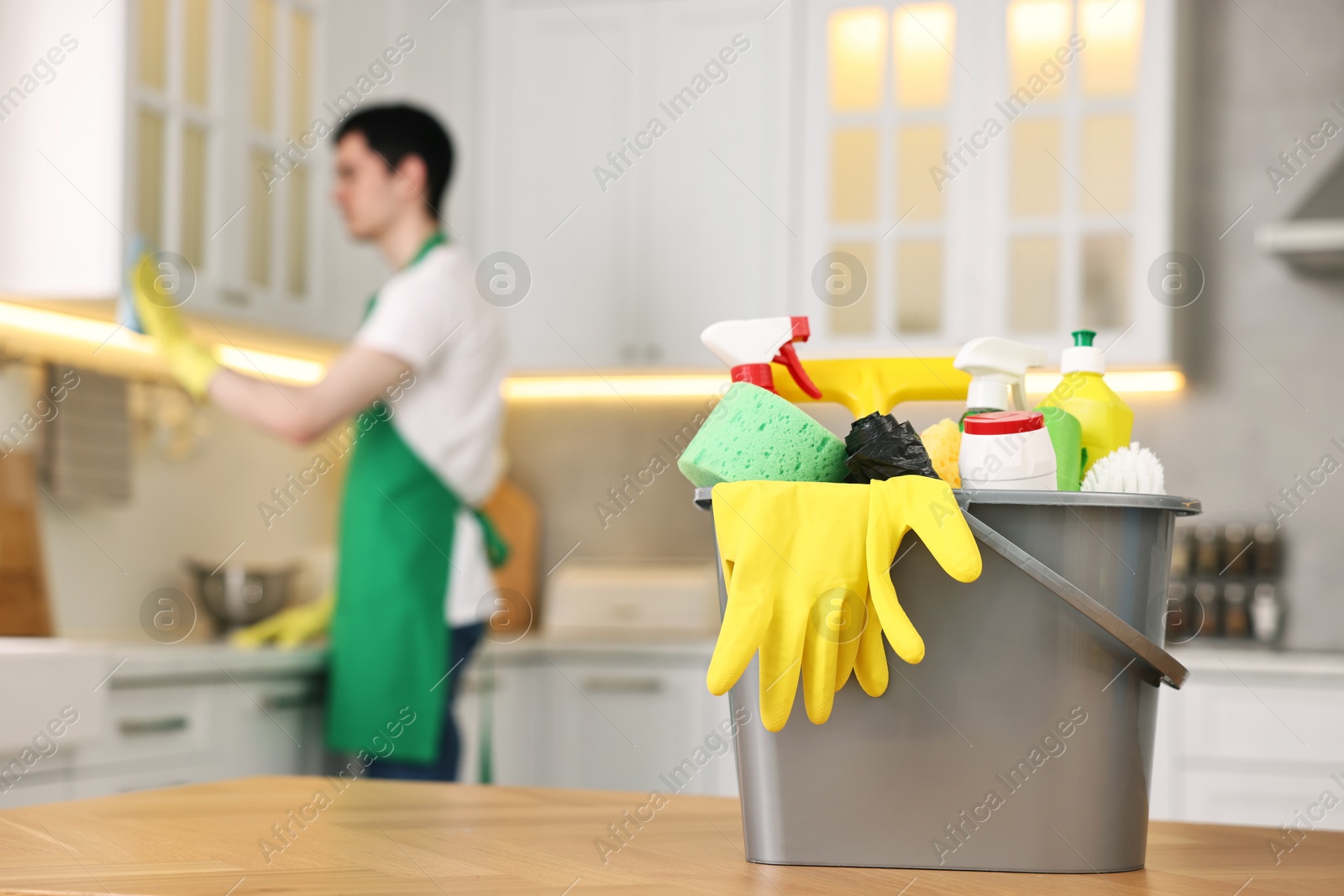 Photo of Professional janitor working in kitchen, focus on bucket with supplies. Cleaning service