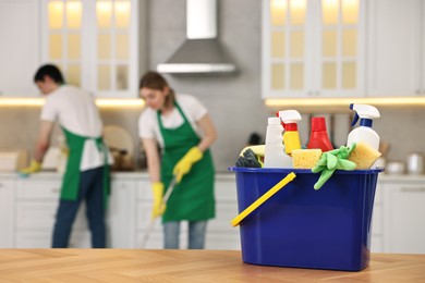 Professional janitors working in kitchen, focus on bucket with supplies. Cleaning service