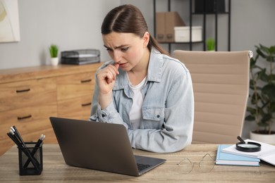 Photo of Embarrassed woman at wooden table with laptop in office