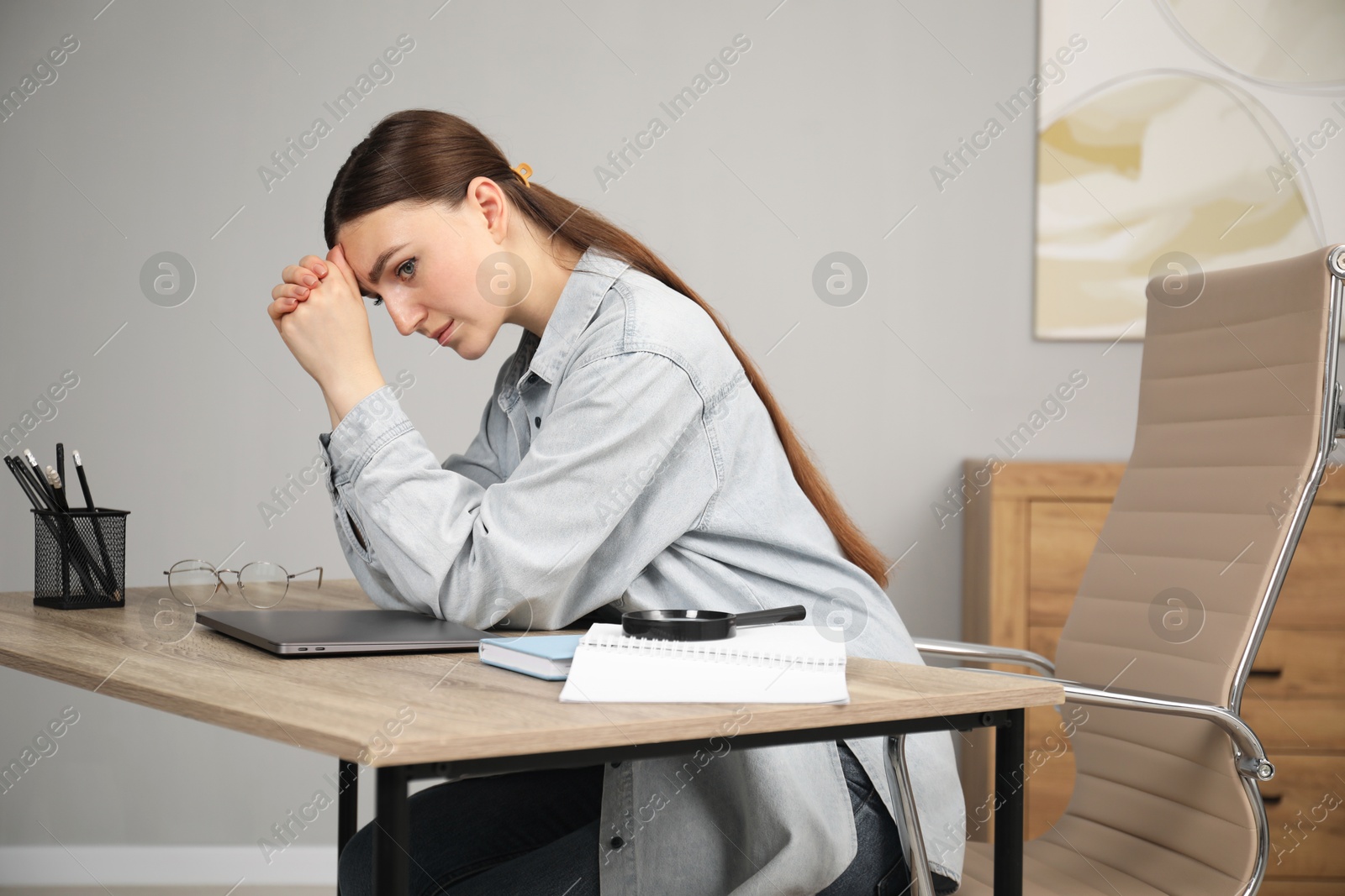 Photo of Embarrassed woman at wooden table with laptop in office