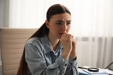 Photo of Embarrassed woman in denim jacket in office