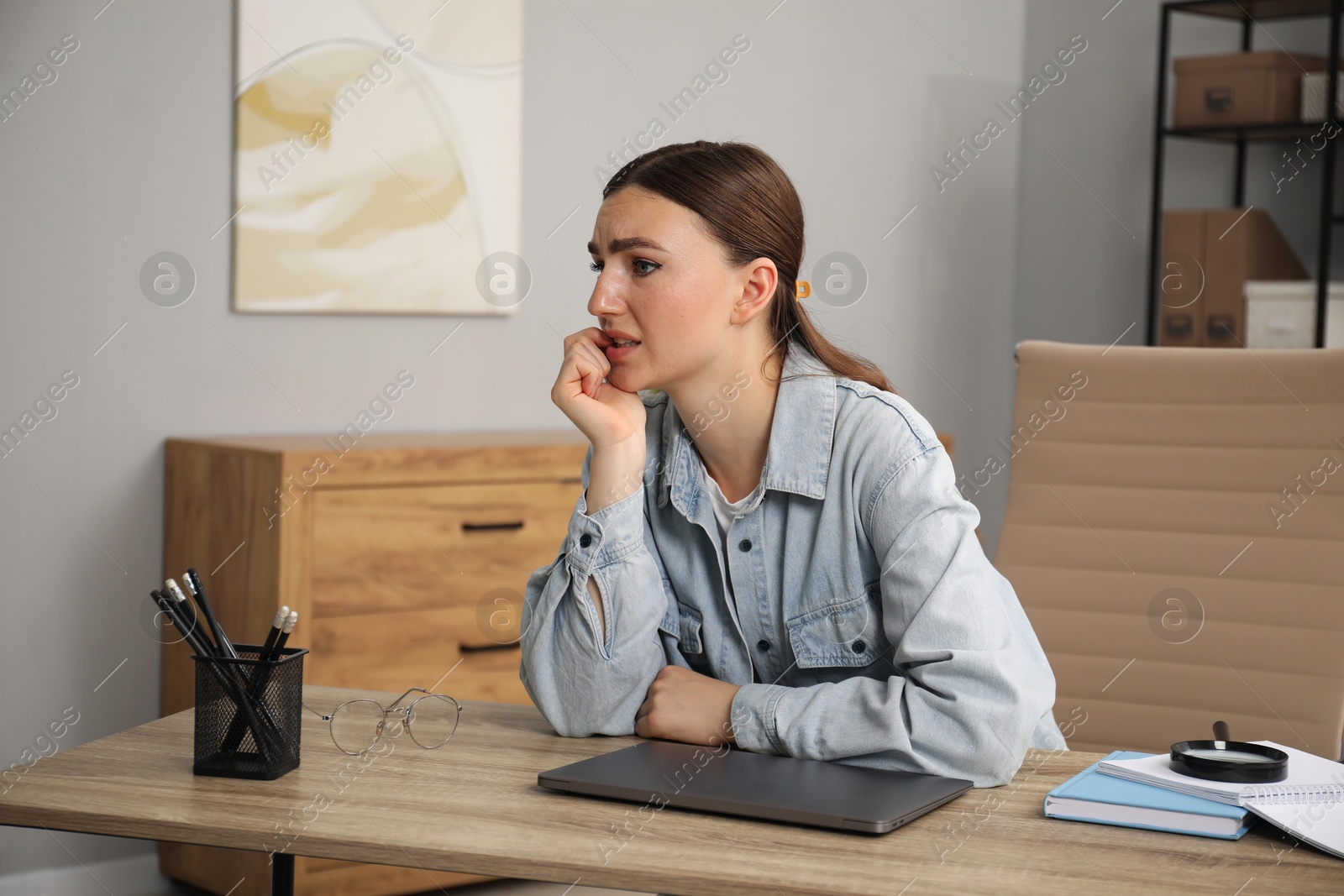 Photo of Embarrassed woman at wooden table with laptop in office